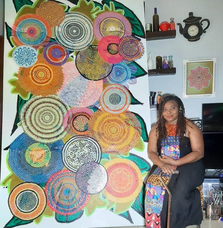 Ijeoma Ogwuegbu sitting with the 60 by 100 inches Dot Art Painting she recently completed. The Painting took her two and half months to complete / Photo credit: Ijeoma Ogwuegbu